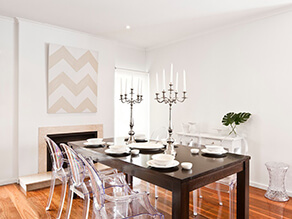 White Modern Dining Room with Timber Floorboards and clear chairs and dark wooden table and candles